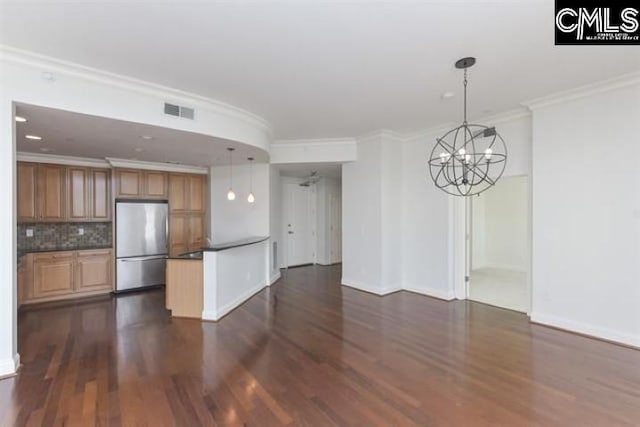 kitchen with visible vents, hanging light fixtures, ornamental molding, freestanding refrigerator, and dark countertops