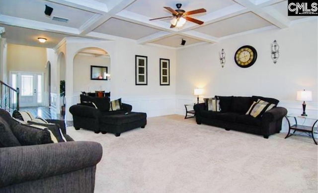 living area with arched walkways, wainscoting, coffered ceiling, and beamed ceiling