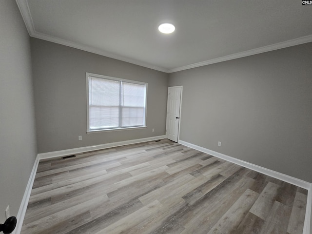 unfurnished room with ornamental molding, light wood-type flooring, visible vents, and baseboards