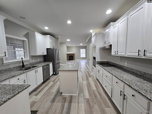 kitchen featuring white cabinets, dark stone counters, a center island, black appliances, and a sink