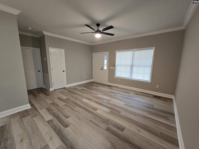 unfurnished room with light wood-style floors, crown molding, and baseboards