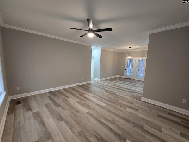 empty room with crown molding, visible vents, light wood-style floors, baseboards, and ceiling fan with notable chandelier