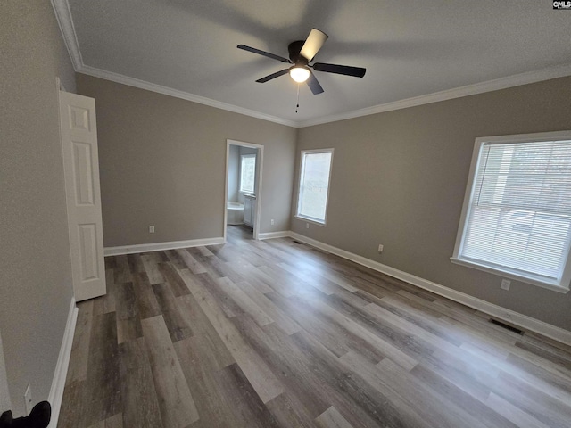 empty room featuring ceiling fan, ornamental molding, wood finished floors, and baseboards