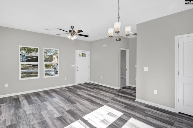 empty room featuring dark wood-style floors, visible vents, baseboards, and ceiling fan with notable chandelier