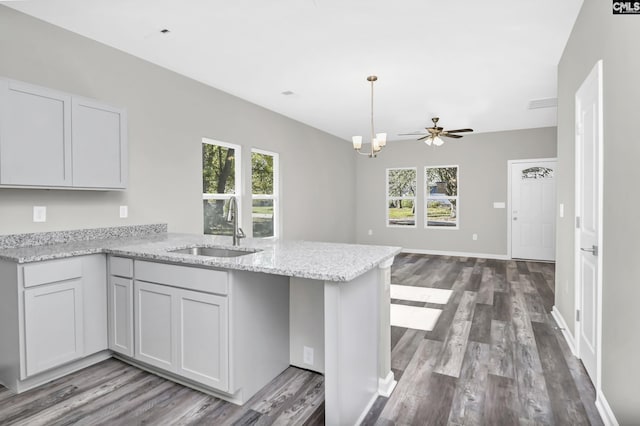 kitchen featuring a peninsula, plenty of natural light, a sink, and light stone countertops