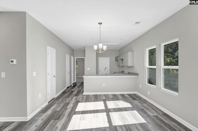 kitchen with pendant lighting, a notable chandelier, white cabinets, a sink, and a peninsula