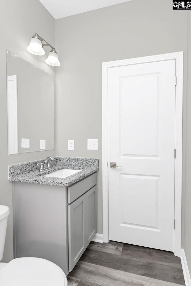 half bath featuring toilet, wood finished floors, and vanity