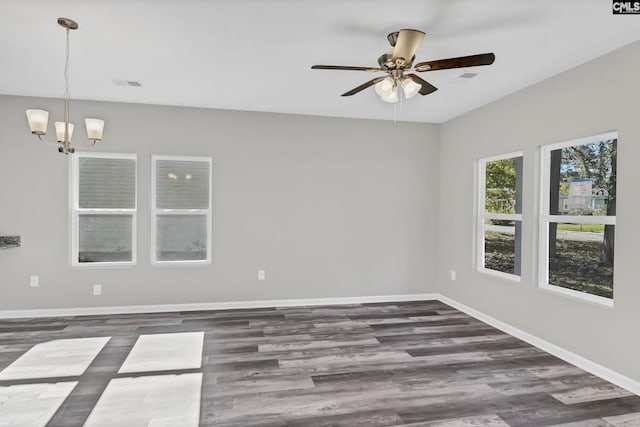 empty room with visible vents, baseboards, dark wood finished floors, and ceiling fan with notable chandelier