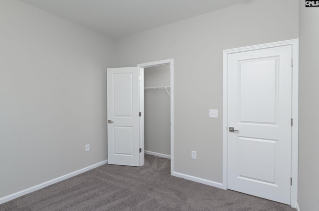 unfurnished bedroom with carpet floors, a spacious closet, a closet, and baseboards