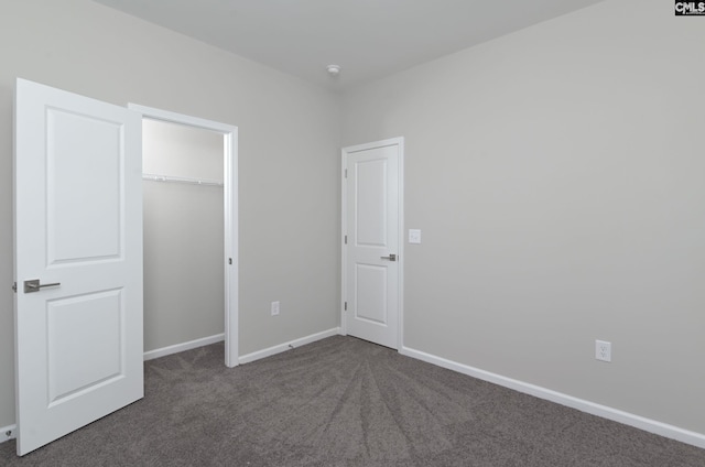 unfurnished bedroom featuring dark colored carpet, a closet, and baseboards