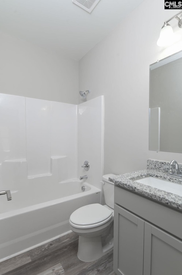 full bathroom featuring toilet, wood finished floors, vanity, visible vents, and shower / washtub combination