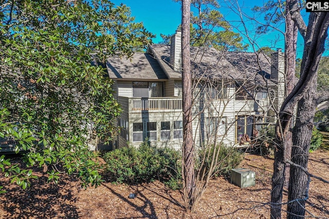 rear view of property with a chimney and a balcony