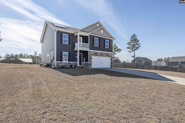 view of front of property featuring driveway, stone siding, an attached garage, and fence