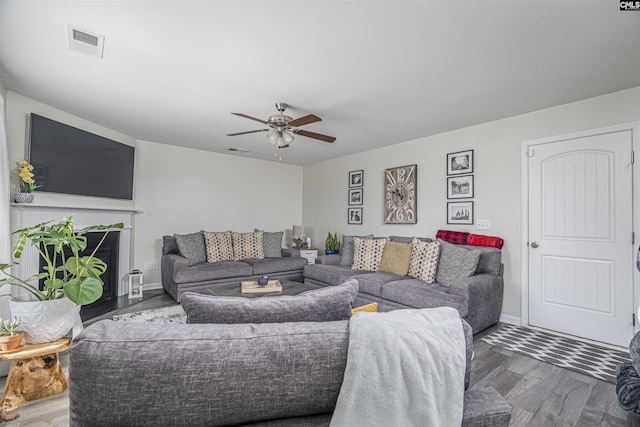 living room featuring baseboards, visible vents, a ceiling fan, dark wood-style floors, and a fireplace