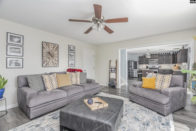 living room with a ceiling fan, baseboards, and wood finished floors