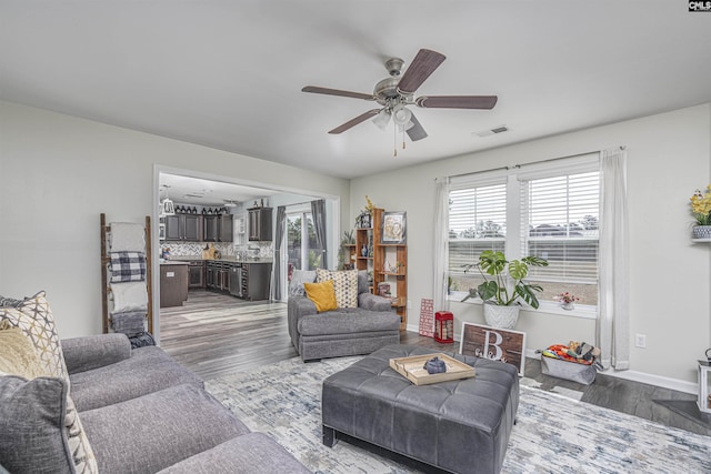 living room with light wood finished floors, baseboards, visible vents, and a ceiling fan