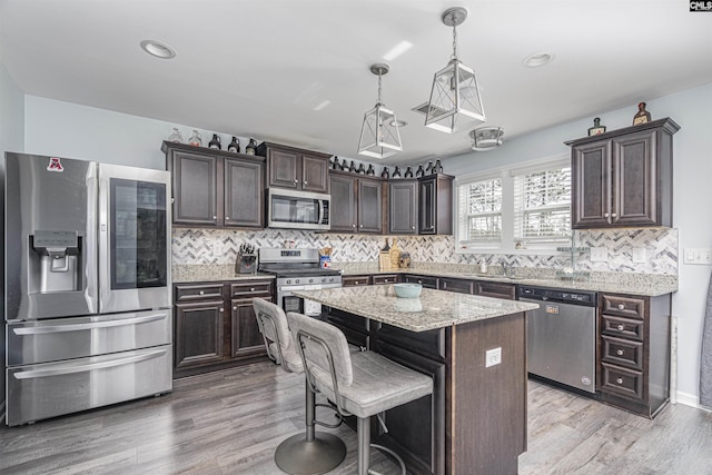 kitchen featuring dark brown cabinetry, appliances with stainless steel finishes, backsplash, a center island, and pendant lighting