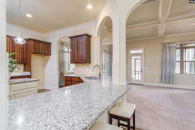 kitchen with tasteful backsplash, white cabinets, light carpet, a sink, and a kitchen bar