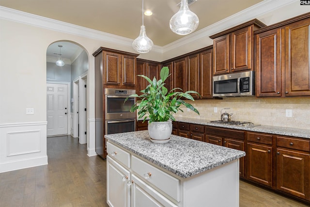 kitchen with appliances with stainless steel finishes, arched walkways, white cabinetry, and hanging light fixtures