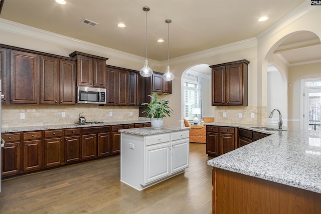 kitchen with dark wood-style flooring, decorative light fixtures, appliances with stainless steel finishes, a sink, and a peninsula