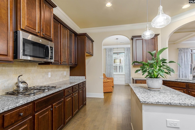 kitchen featuring light stone counters, dark wood-style flooring, appliances with stainless steel finishes, decorative backsplash, and crown molding