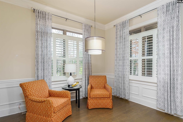 living area with dark wood-style floors, a decorative wall, wainscoting, and crown molding