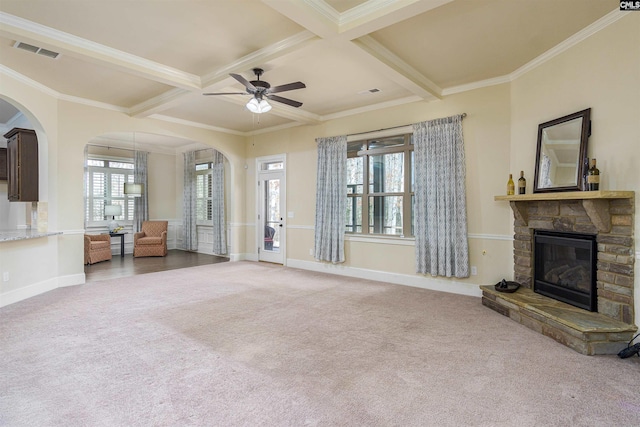 unfurnished living room with arched walkways, beam ceiling, a fireplace, visible vents, and carpet flooring