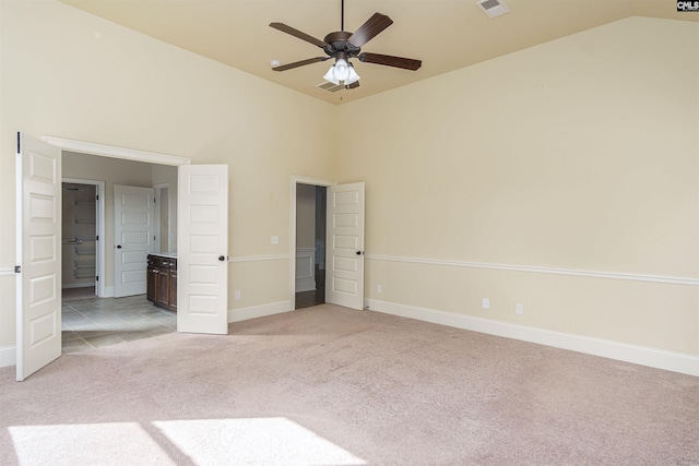 unfurnished bedroom featuring light carpet, high vaulted ceiling, visible vents, and baseboards