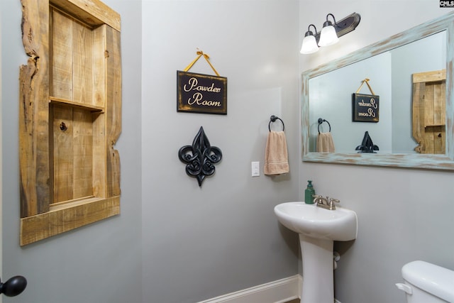 bathroom with toilet, baseboards, and a sink