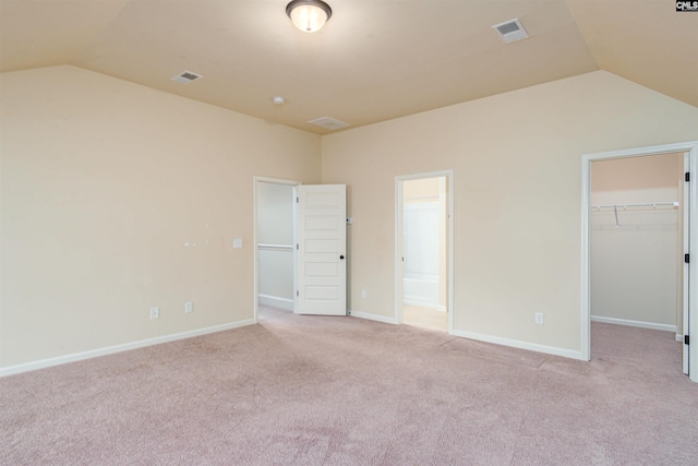 unfurnished bedroom with light carpet, a spacious closet, visible vents, and lofted ceiling