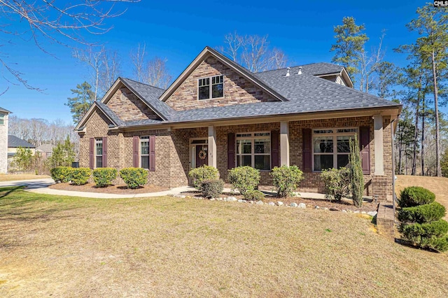 craftsman-style house featuring a shingled roof, brick siding, a porch, and a front lawn