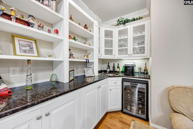 bar featuring light wood-style floors, wine cooler, crown molding, and a dry bar