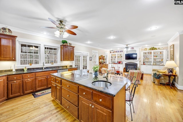 kitchen featuring a center island with sink, dark stone counters, open floor plan, and a sink