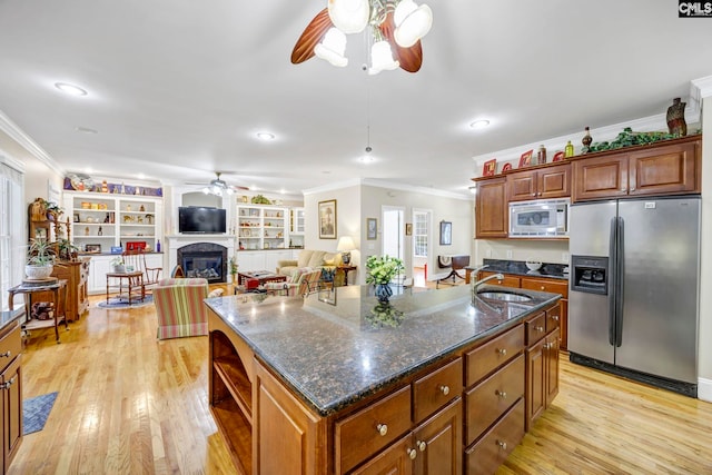 kitchen featuring a center island with sink, light wood finished floors, appliances with stainless steel finishes, open floor plan, and a sink