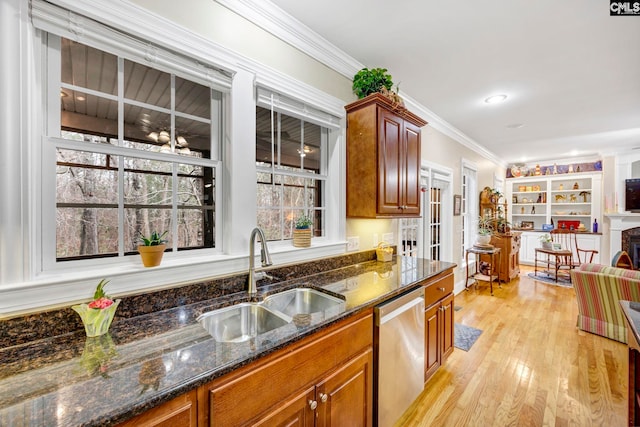 kitchen featuring dark stone counters, dishwasher, light wood-style flooring, ornamental molding, and a sink