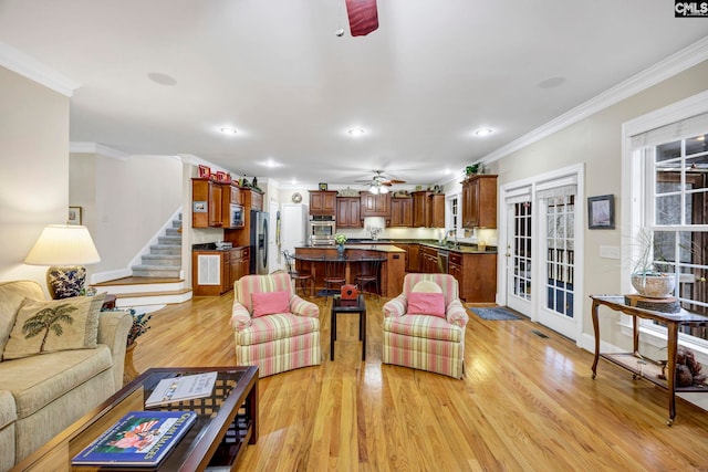 living room featuring light wood finished floors, ceiling fan, ornamental molding, stairs, and recessed lighting