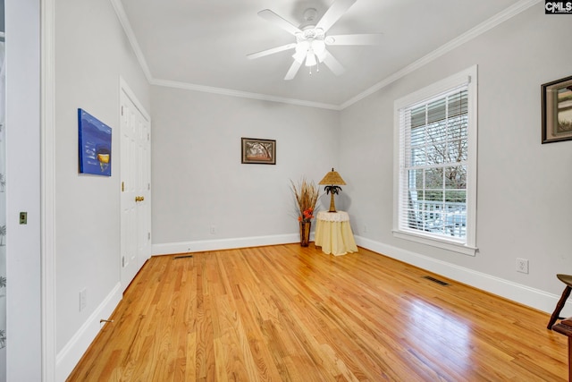 spare room featuring light wood-style floors, a ceiling fan, baseboards, and crown molding