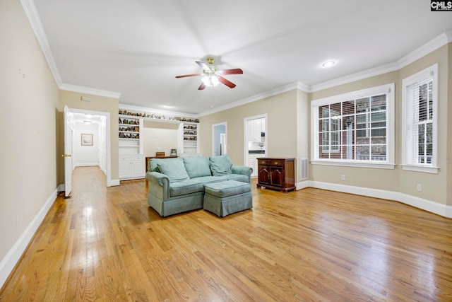 living room featuring visible vents, ornamental molding, ceiling fan, light wood-type flooring, and baseboards