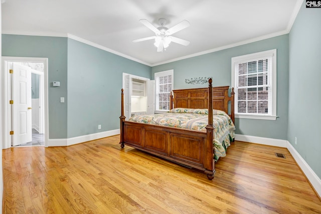 bedroom with light wood-style floors, visible vents, ornamental molding, and baseboards