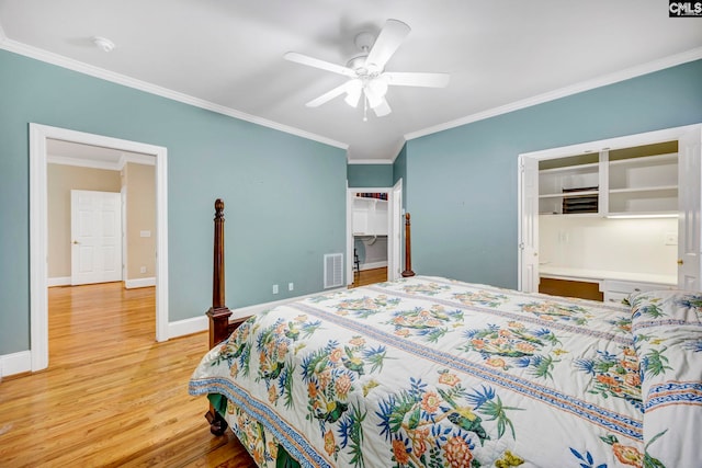 bedroom with ornamental molding, a spacious closet, baseboards, and wood finished floors