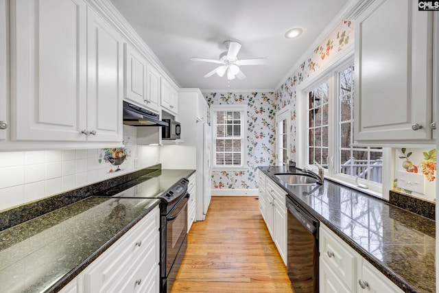 kitchen featuring black appliances, under cabinet range hood, white cabinets, and wallpapered walls