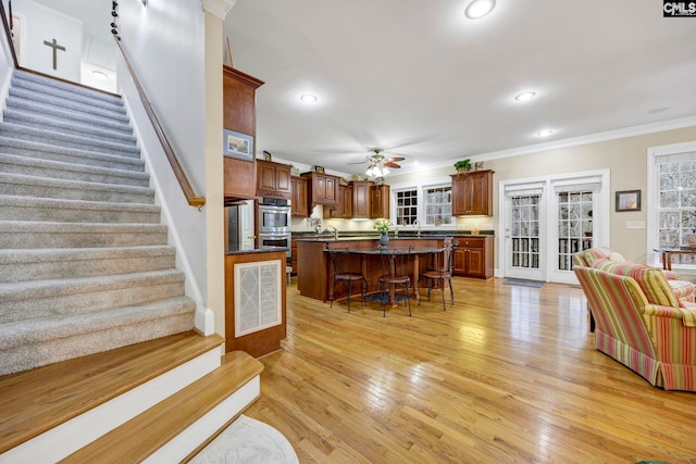 kitchen with a breakfast bar, open floor plan, ornamental molding, a center island, and dark countertops