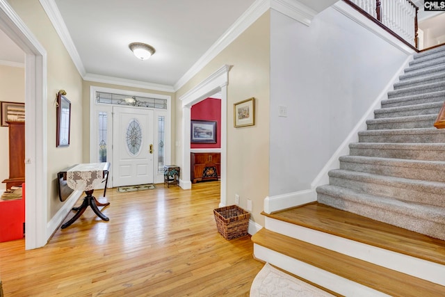 entryway with crown molding, light wood-style flooring, baseboards, and stairs