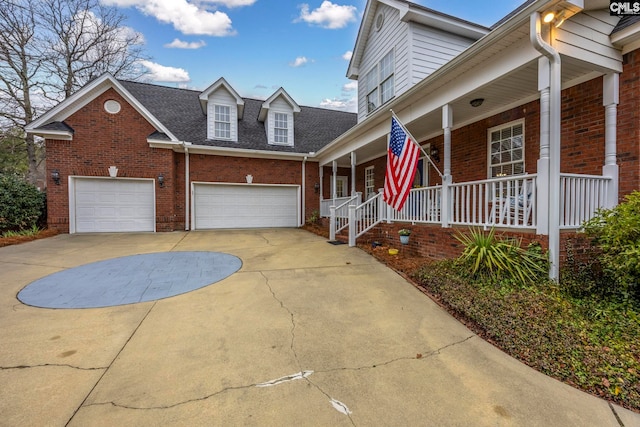 view of front facade with a shingled roof, covered porch, brick siding, and driveway