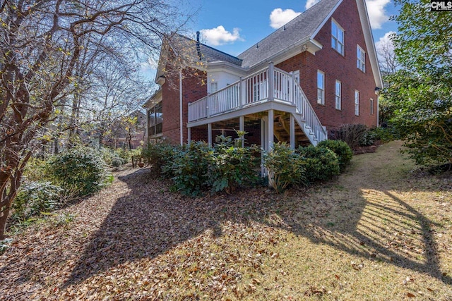 rear view of property featuring brick siding, a lawn, and a deck