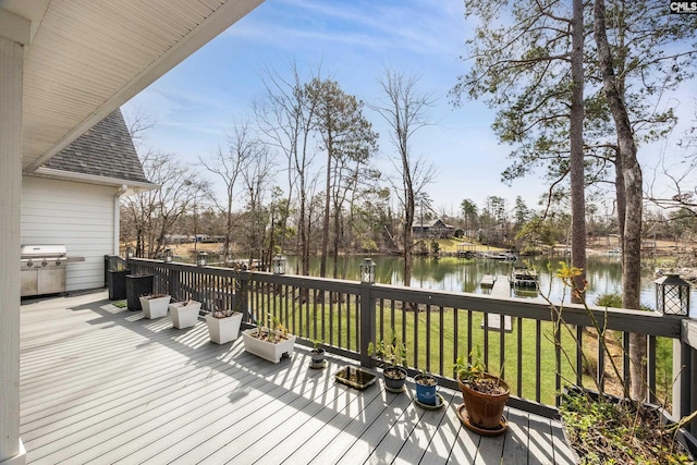 wooden terrace featuring a water view, grilling area, and a lawn