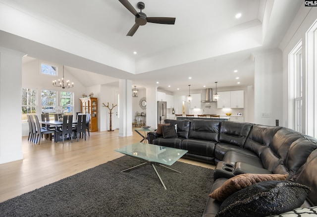 living room with ornamental molding, light wood finished floors, ceiling fan with notable chandelier, and recessed lighting