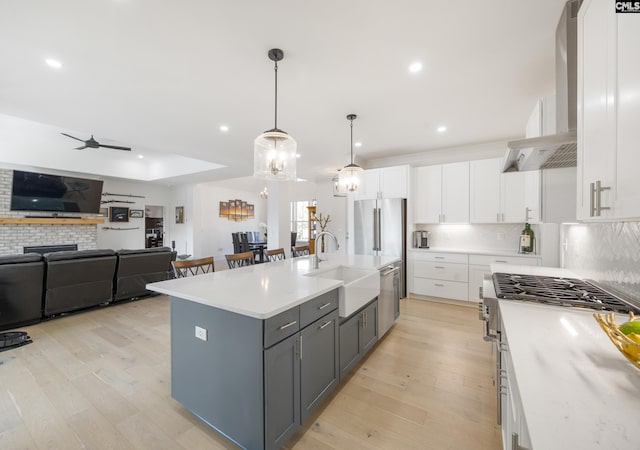 kitchen featuring a sink, white cabinetry, light countertops, hanging light fixtures, and a center island with sink