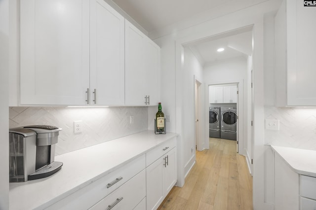 kitchen with white cabinetry, light wood-type flooring, light countertops, and separate washer and dryer