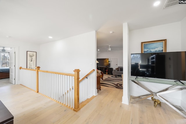 hallway with light wood-type flooring, visible vents, an upstairs landing, and recessed lighting